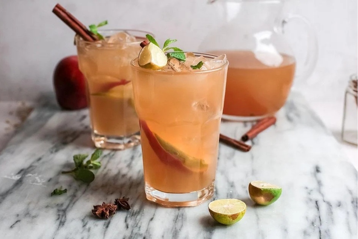 Two glasses of apple cider, perfect for Thanksgiving gatherings, placed elegantly on a marble table.