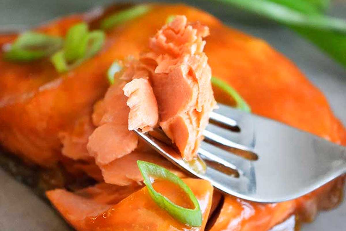 A fork is being used to eat a piece of salmon.