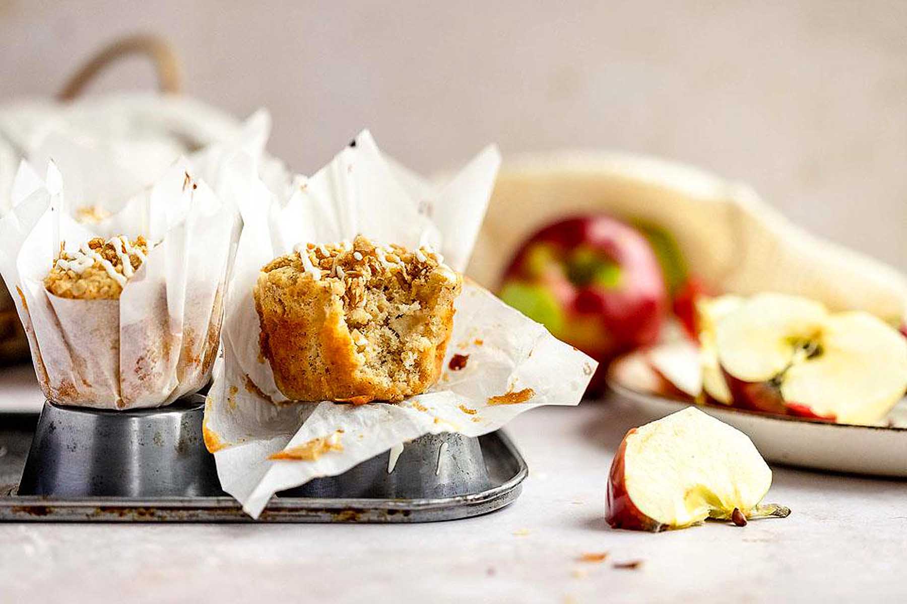 Apple muffins on a tray with apples.