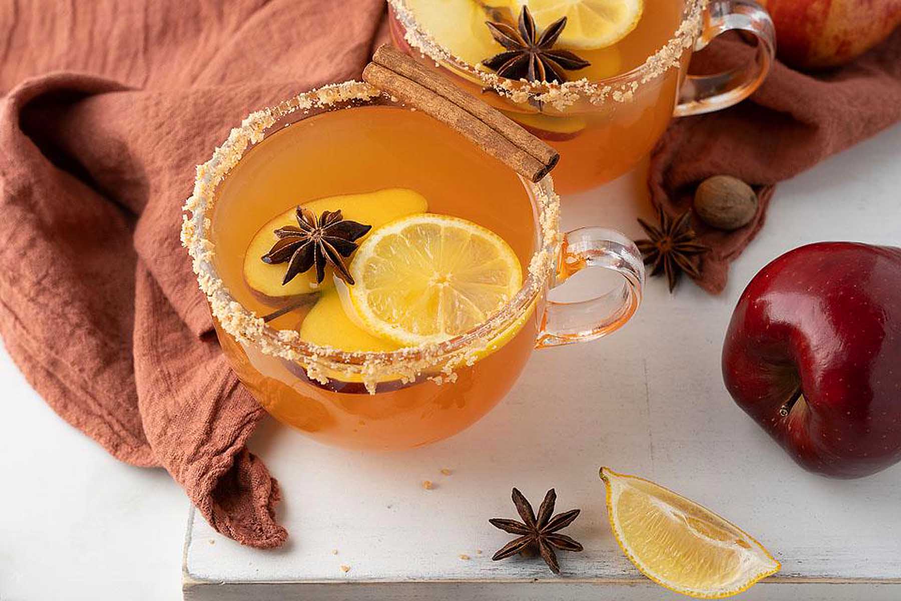 Two mugs of apple cider with cinnamon and star anise.