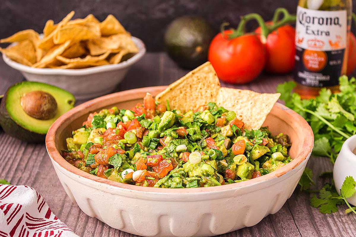 A bowl of guacamole on a wooden table.