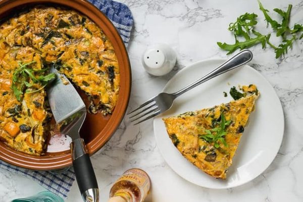 A quiche with spinach and mushrooms on a plate.