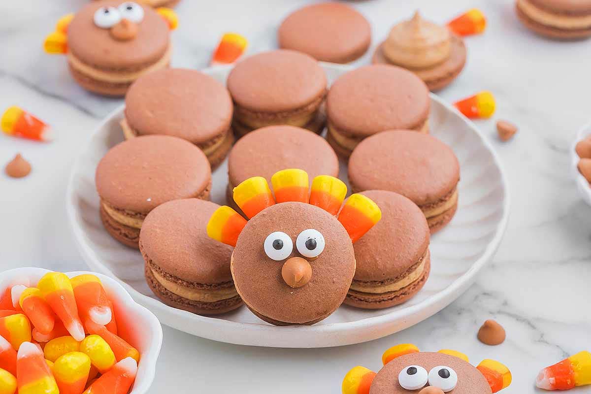 Thanksgiving macarons with candy corn on a plate.
