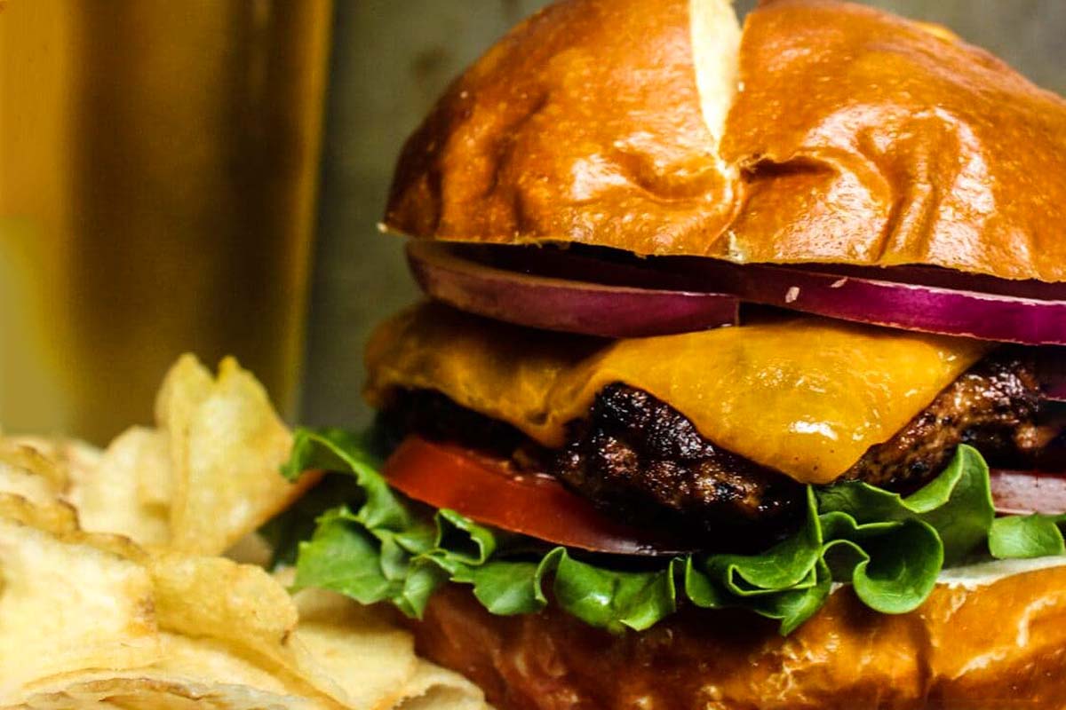 A burger with fries and beer on a table.