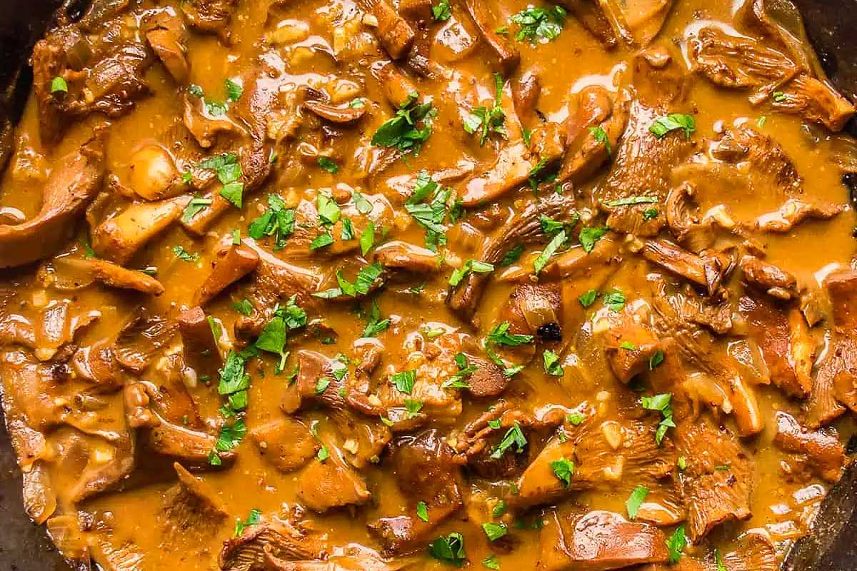 A hearty skillet filled with mushrooms and gravy, perfect for a vegan Thanksgiving meal.