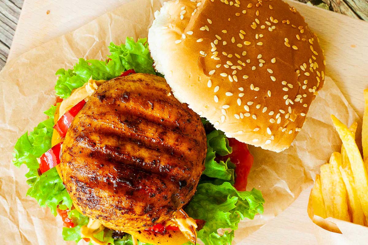 A burger with fries and lettuce on a piece of paper.