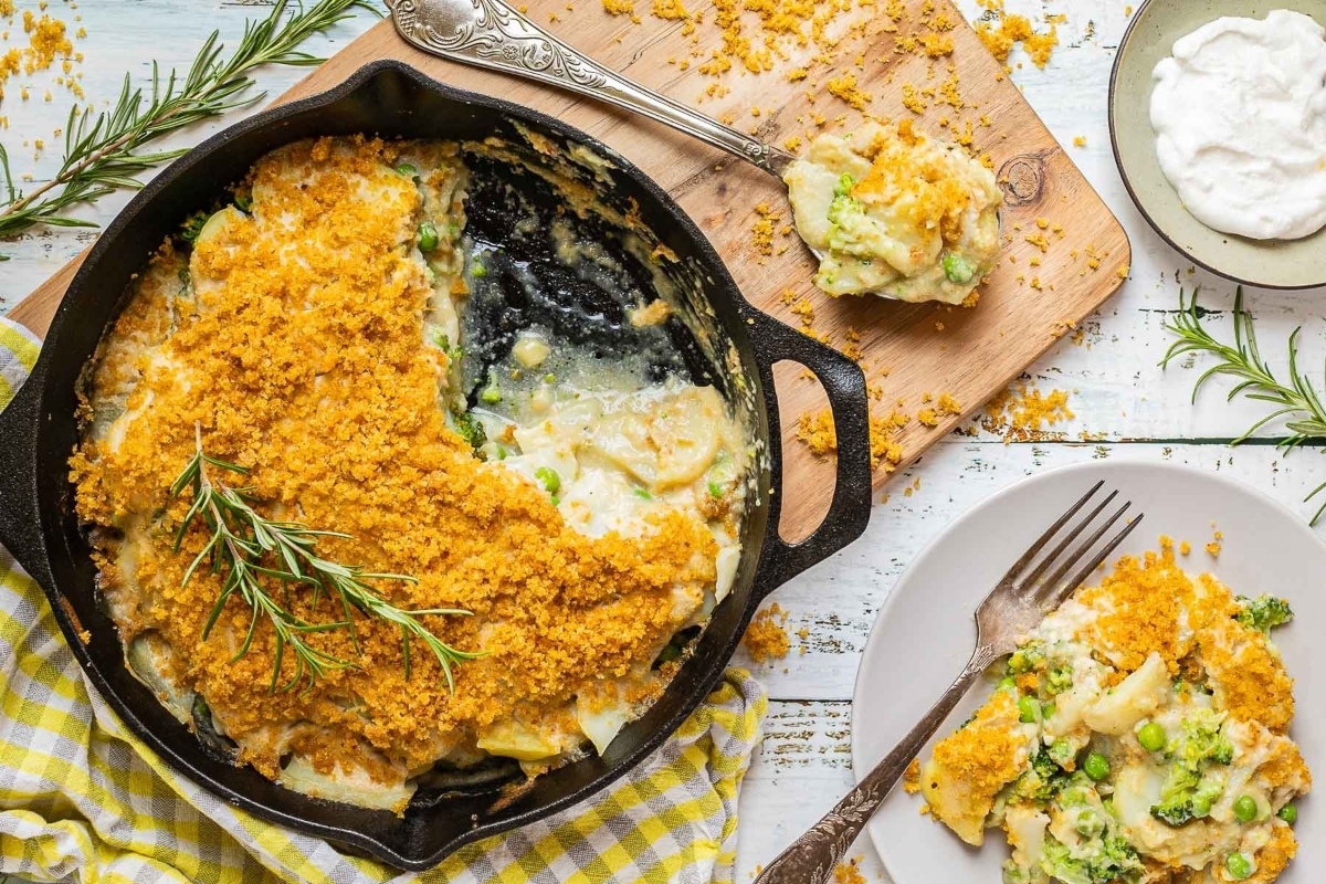 A skillet with broccoli and potato casserole on a wooden table.