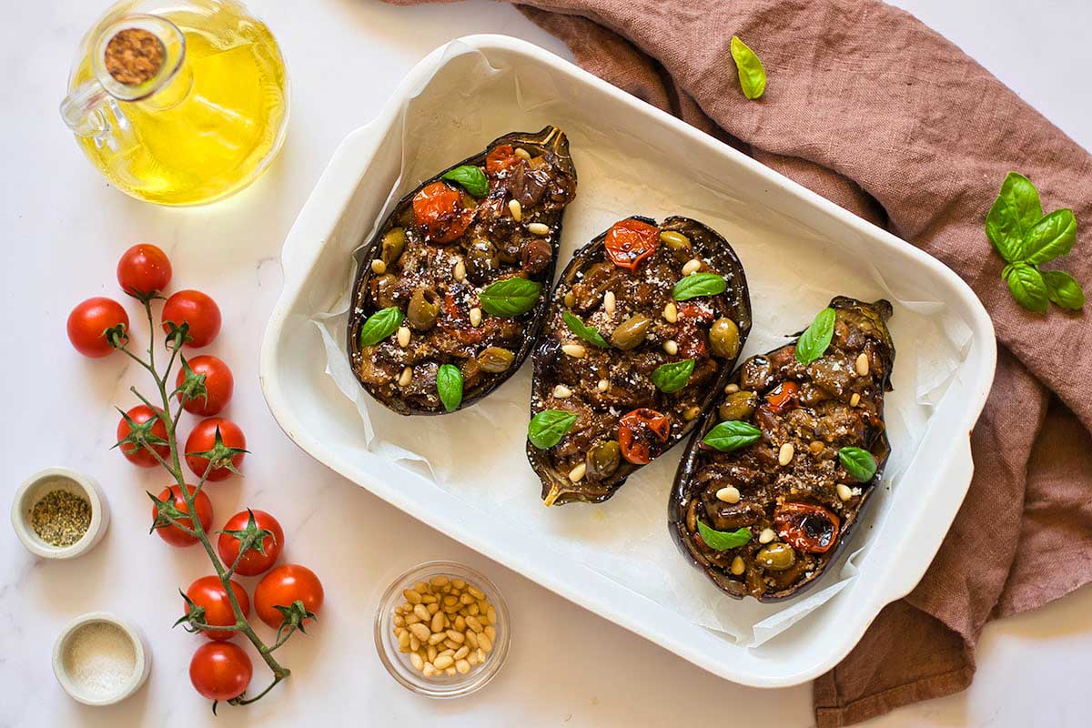 Stuffed eggplants with tomatoes and herbs on a white plate.