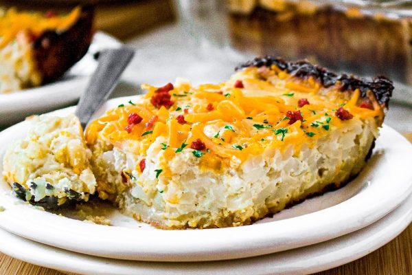 A piece of potato pie on a plate with a fork.