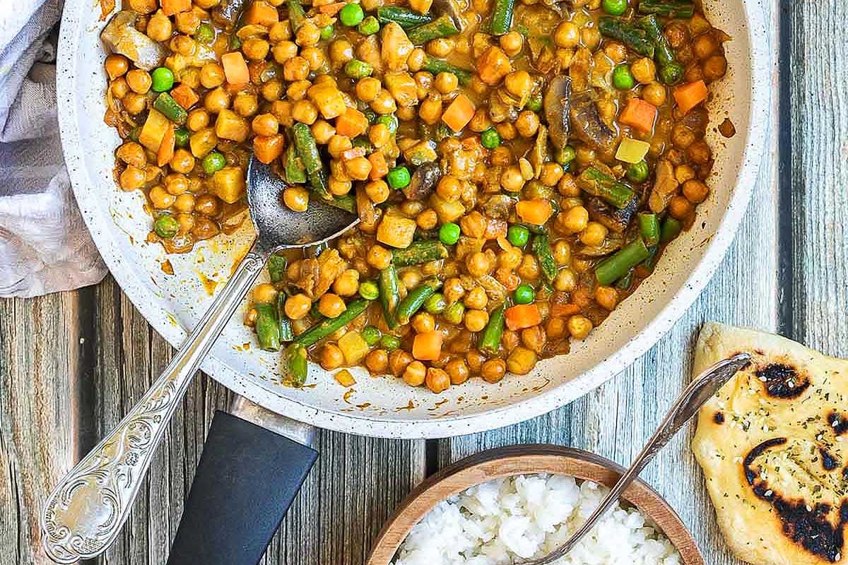 Chickpeas in a skillet with rice and a spoon.
