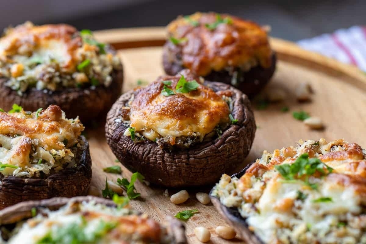 New Year's Eve appetizers, stuffed mushrooms with cheese and parsley on a wooden board.