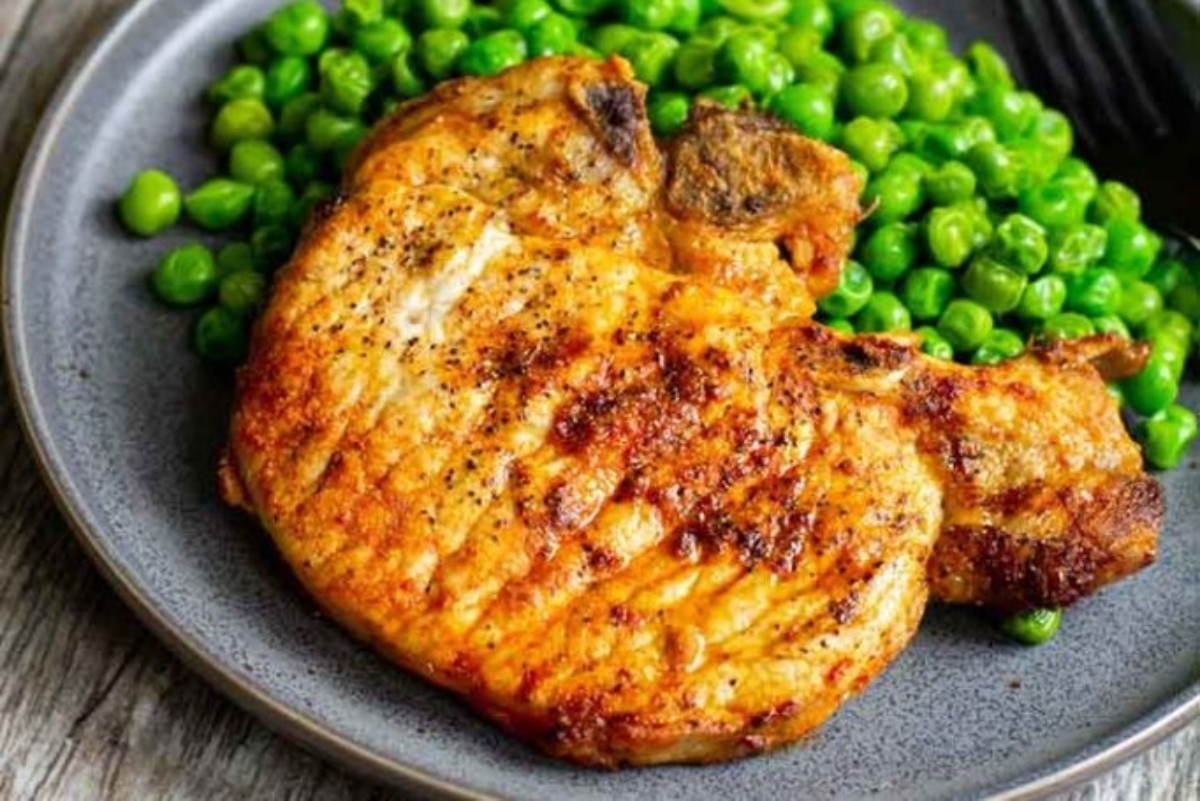 Pork chops served with peas on a plate make for a comforting winter dinner.