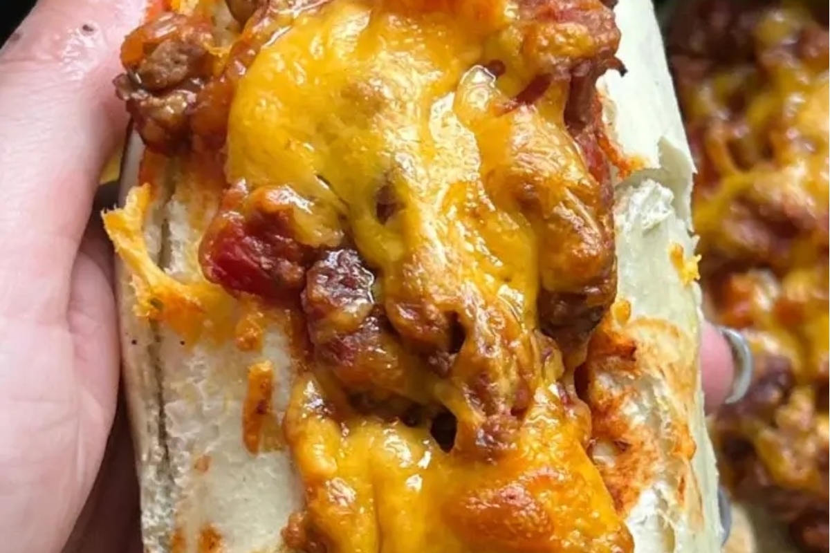 A person is holding a hot dog with cheese on it, relishing in its tasty chili topping.