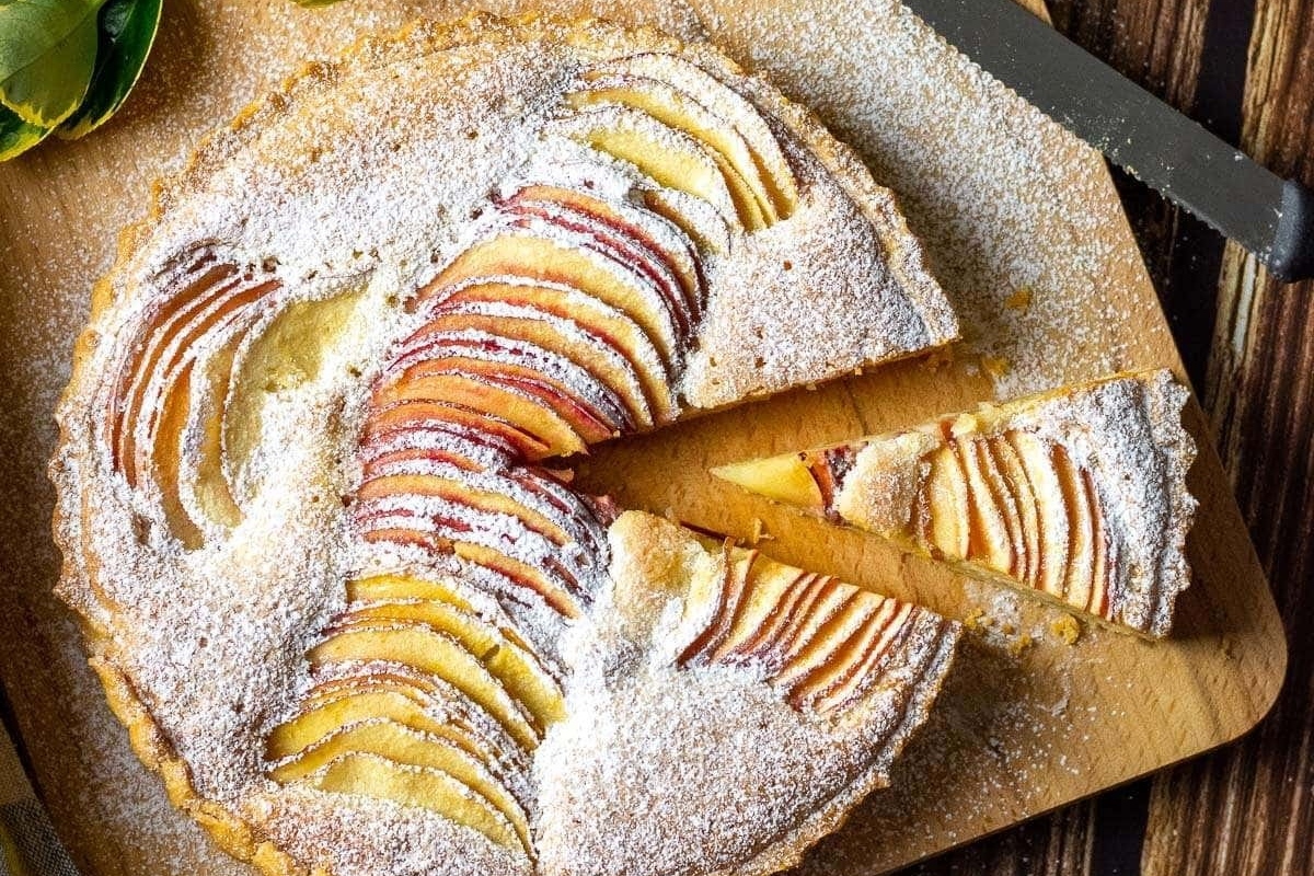A delectable recipe for peach tart, beautifully presented on a rustic wooden cutting board.