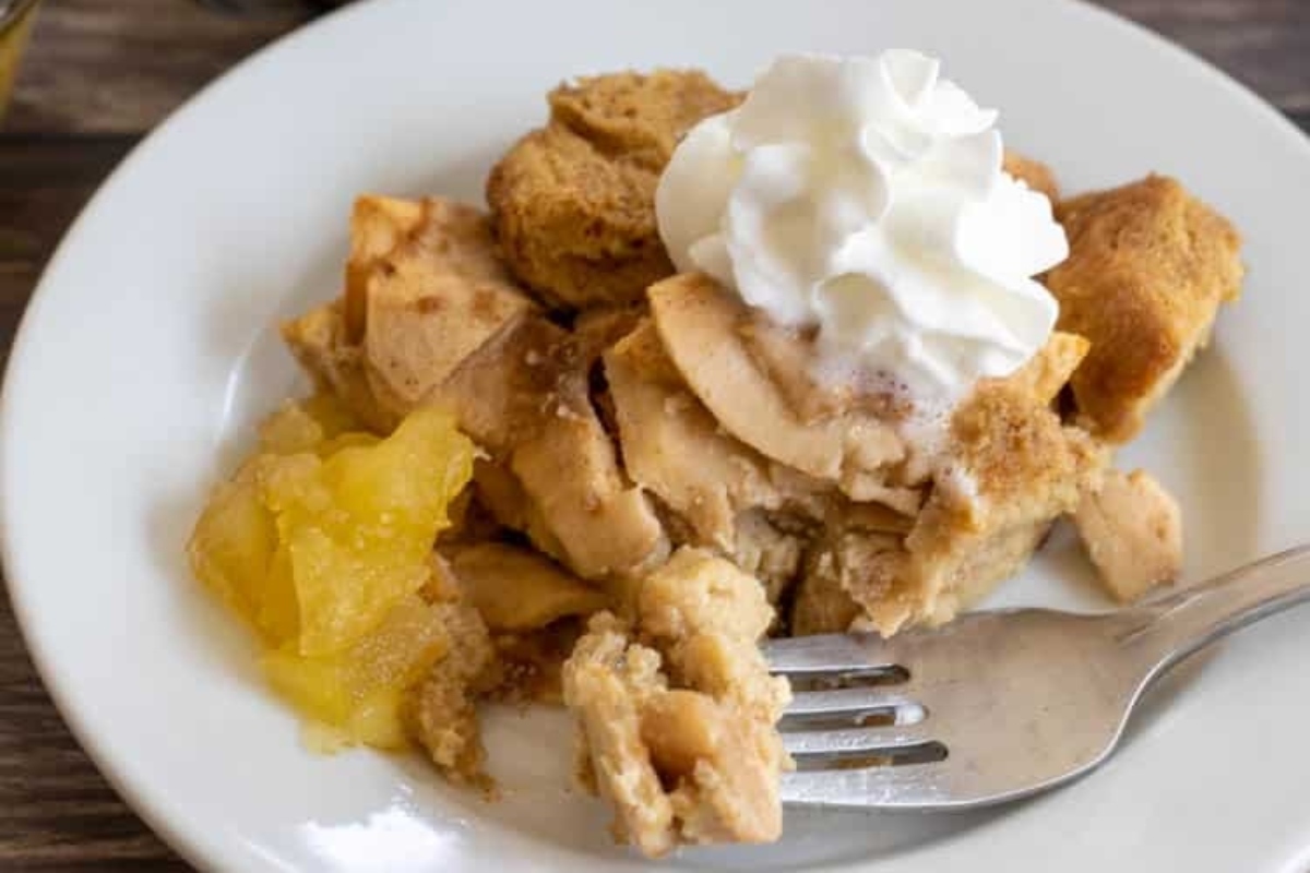 A Christmas-inspired slice of apple bread pudding, perfectly baked and served with a dollop of whipped cream on a plate.