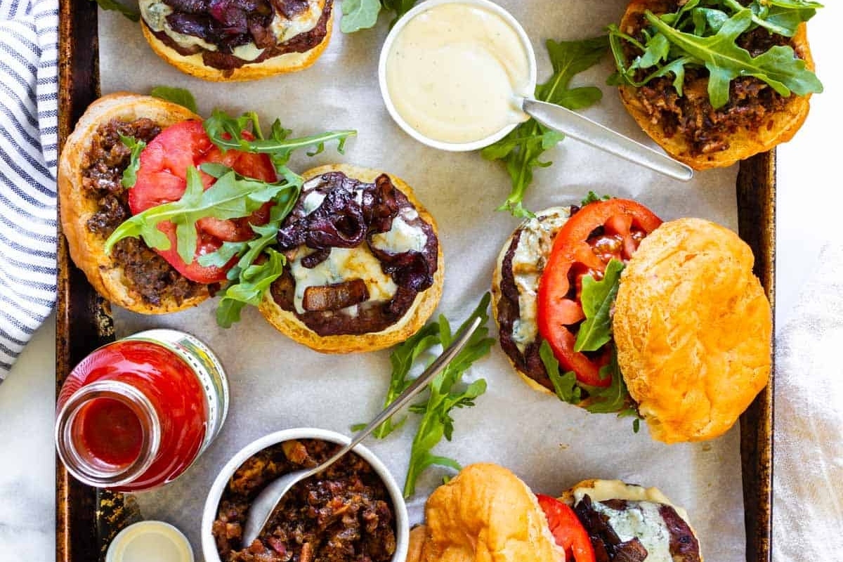 A tray of burgers, perfect for game day mains, on a baking sheet.
