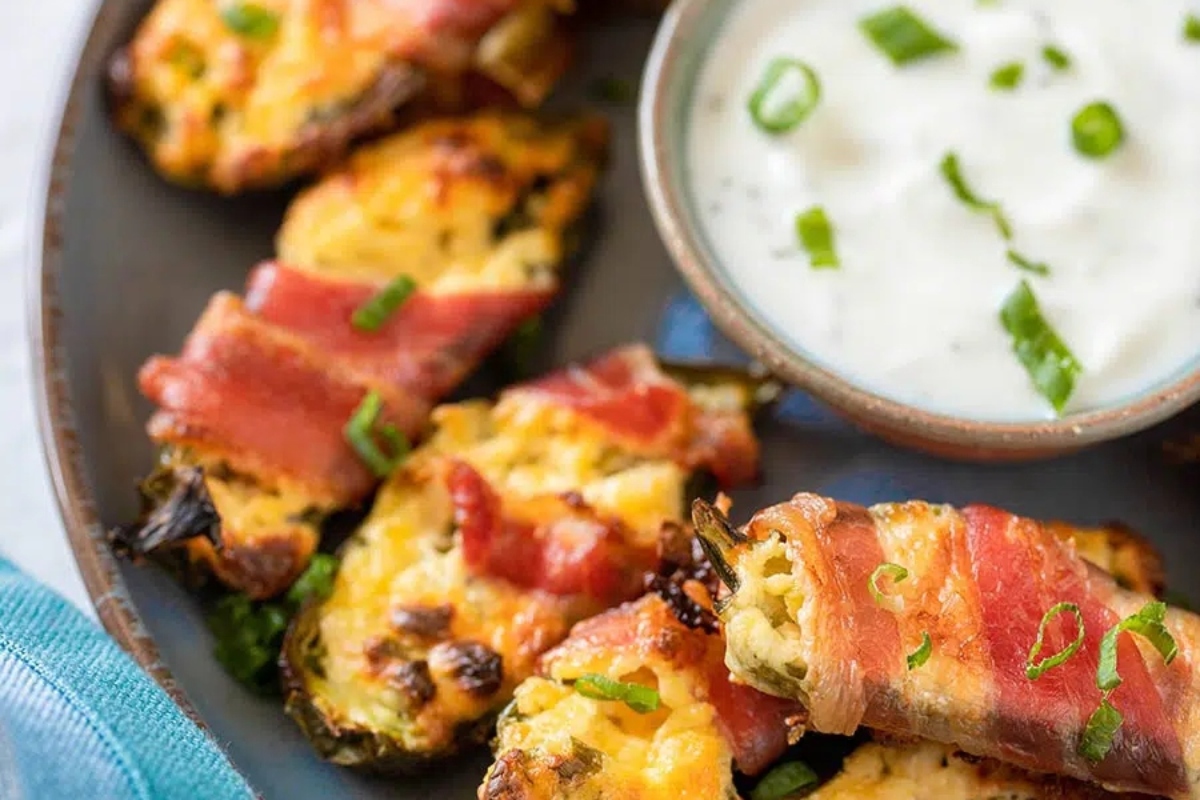 Bite-sized bacon wrapped acorn squash perfect for game day, served with a side of sour cream.