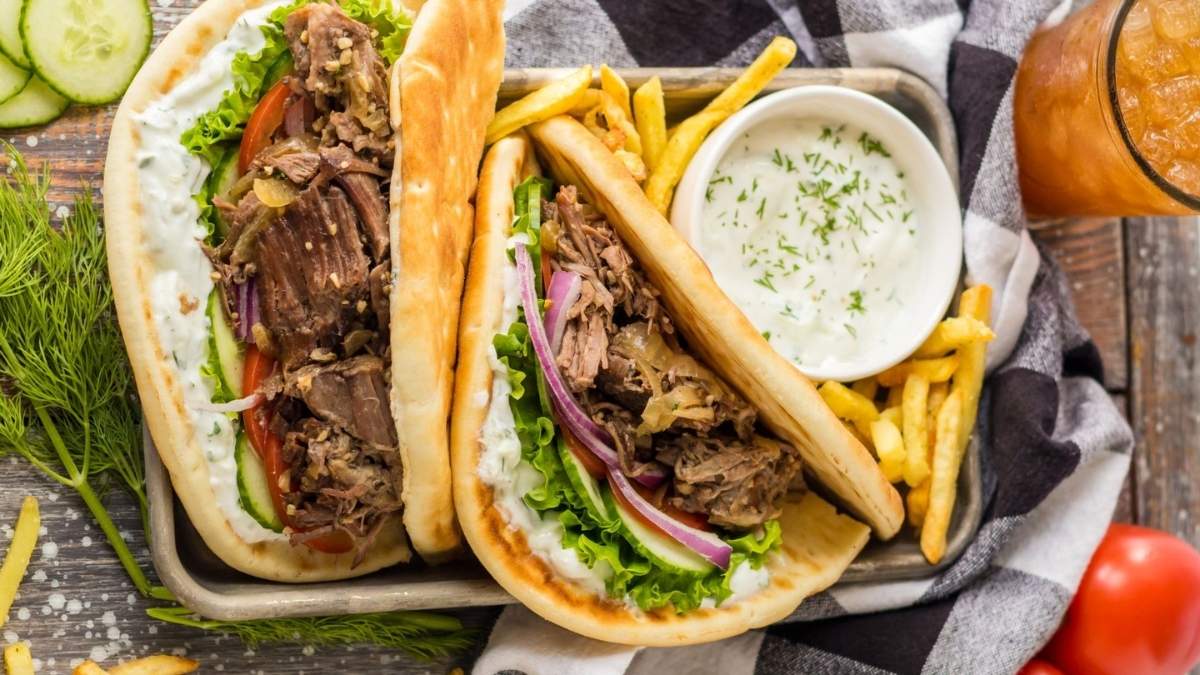 Two shared pitas with comforting meat and vegetable fillings on a wooden table.