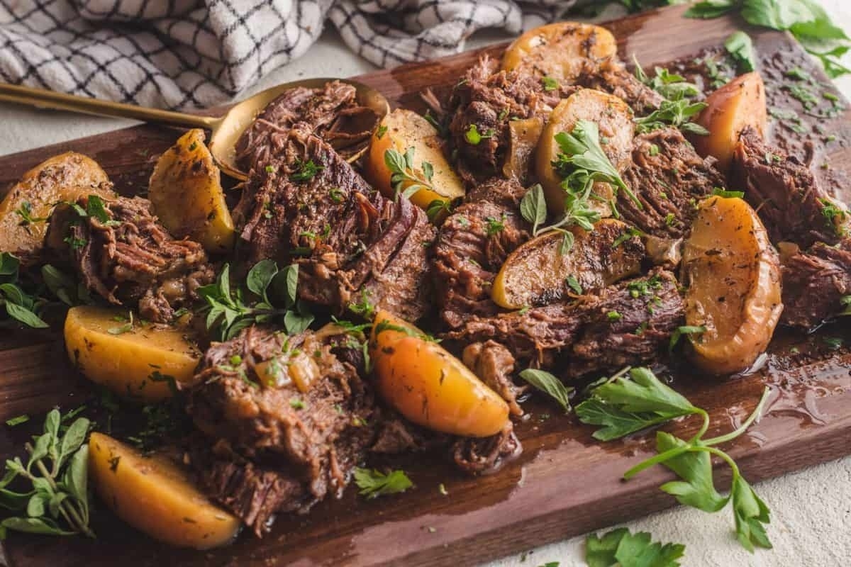 Christmas dinner featuring roasted beef with potatoes and herbs on a cutting board.
