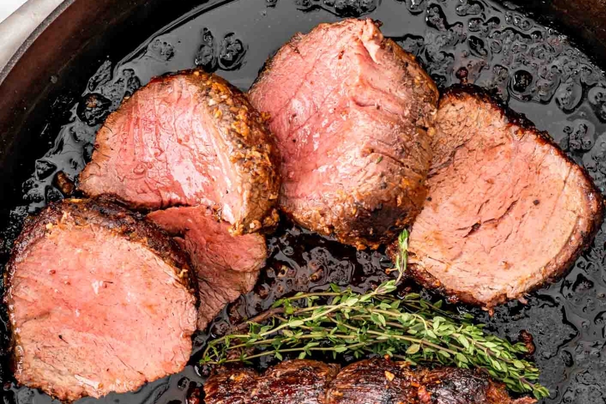 Christmas dinner of beef tenderloin cooked in a skillet with sprigs of thyme.