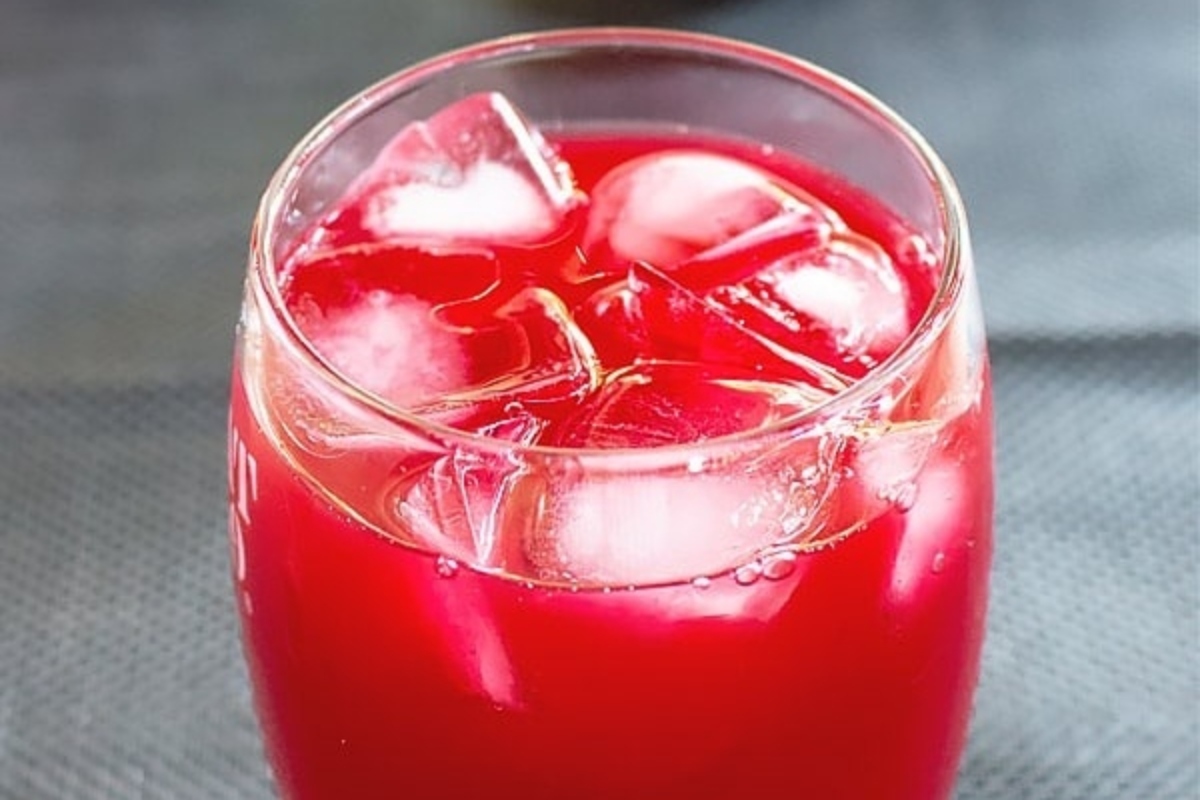 A glass of red drink with ice cubes.