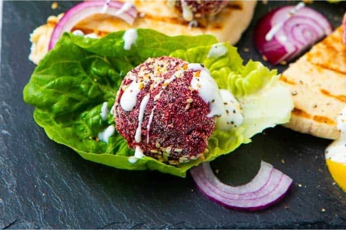Beet balls served on a plate with lettuce and onions, showcasing a delightful beet recipe.