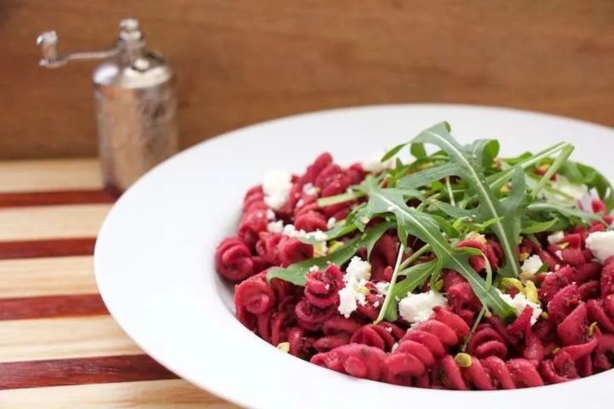 Delicious beetroot pasta with arugula and pistachios, perfect for beet lovers.