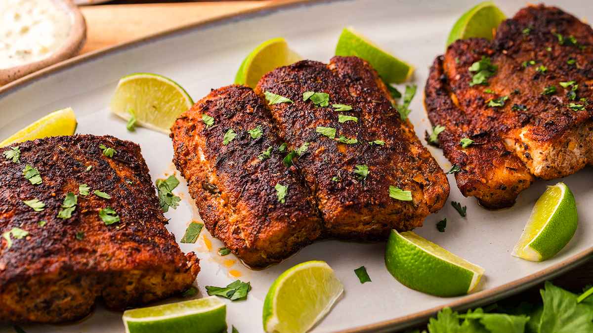 Three pieces of grilled salmon on a plate with lime wedges, a healthy and delicious dinner option.