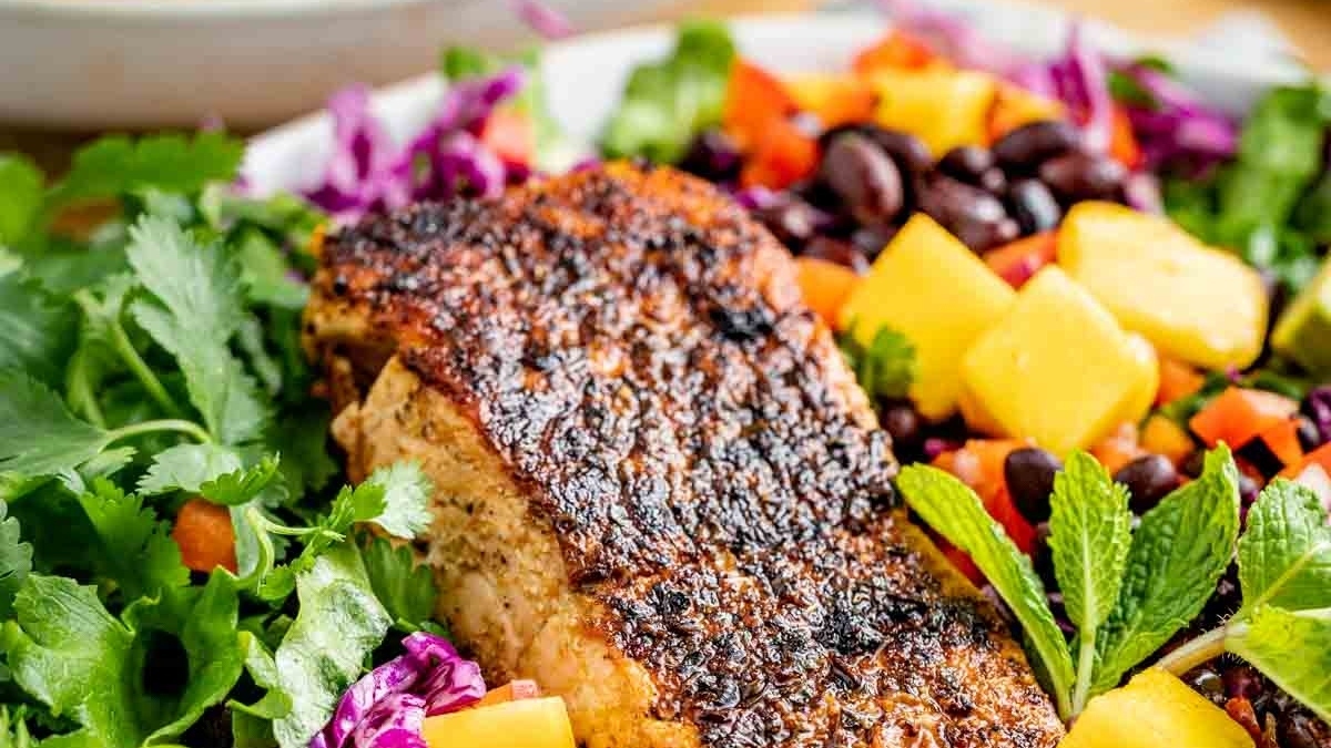 A plate of grilled salmon and black beans, perfect for dinner, on a white plate.