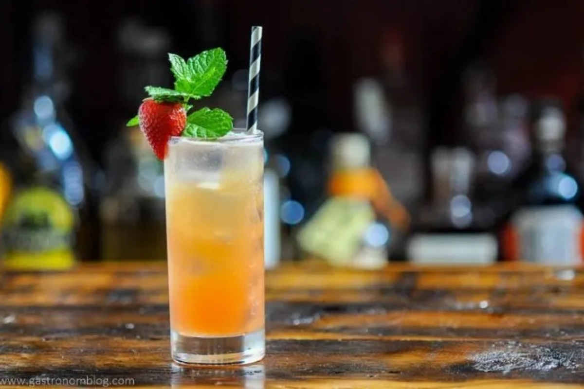 A romantic cocktail with strawberries and mint on top of a wooden table perfect for Valentine's Day.