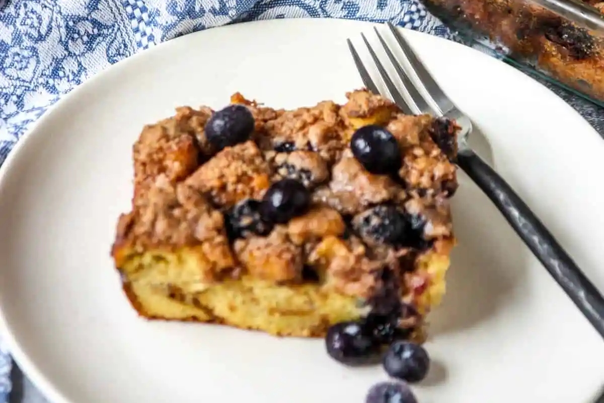 A slice of sweet blueberry bread pudding on a plate with a fork.