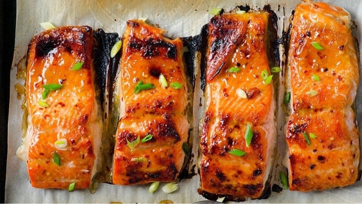 Four salmon fillets on a baking sheet ready for dinner.