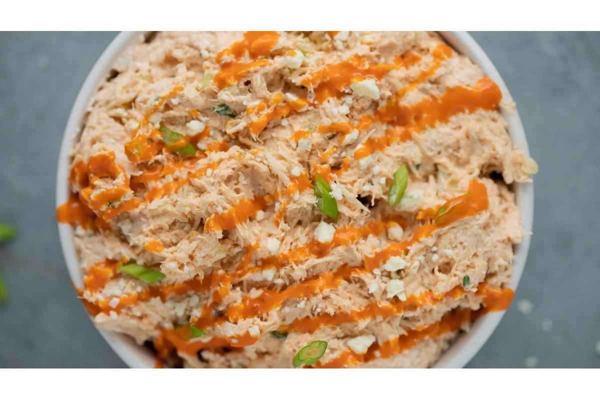 A healthy bowl of high protein chicken dip with sauce and green onions, perfect for lunches.