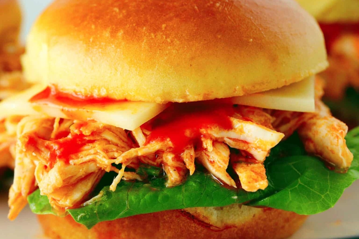 Bite-sized game day chicken sliders with ketchup and lettuce on a plate.