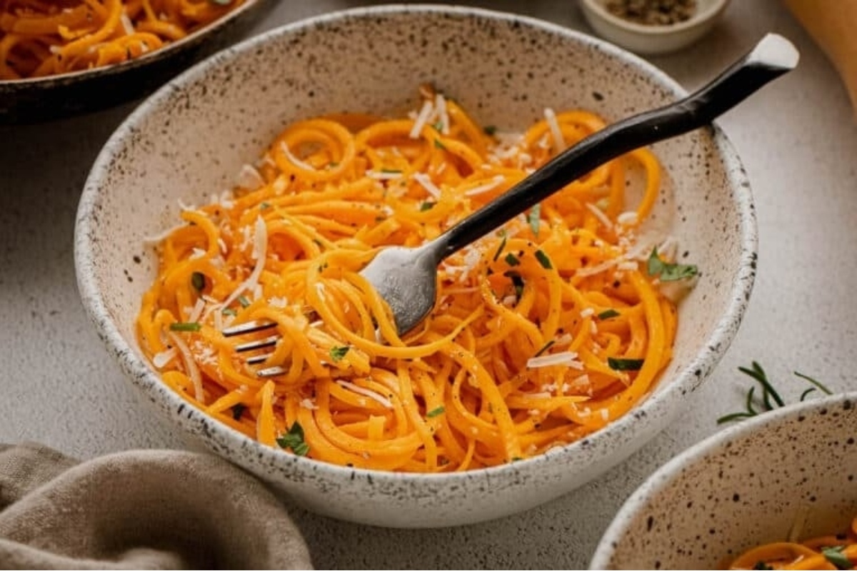 A bowl of spiralized spaghetti with parmesan cheese and herbs.