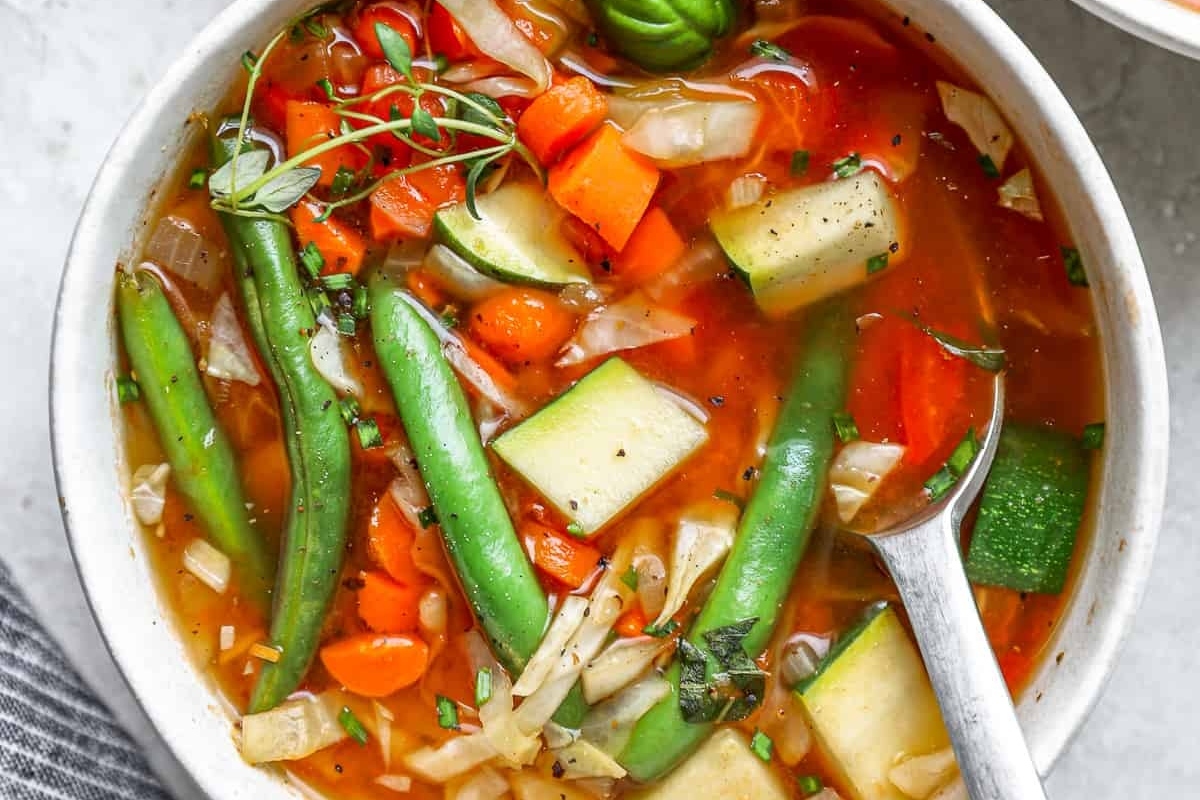 A delicious bowl of homemade vegetable soup served with a spoon.