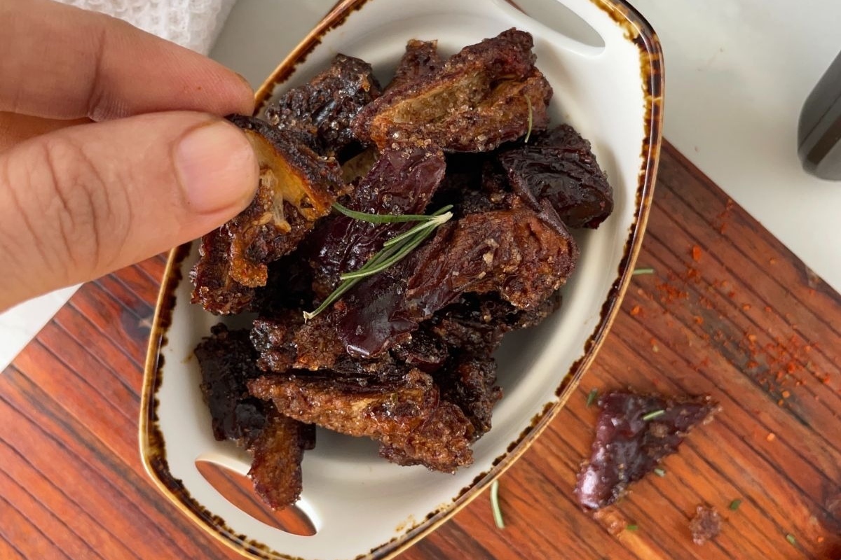 A person is holding a jar of roasted chile peppers, a perfect gift for spicy food enthusiasts.
