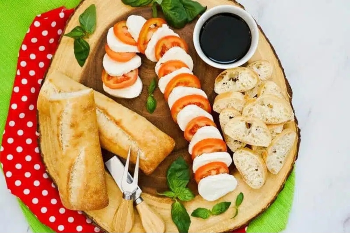 An appetizer plate with cheese, tomatoes and bread on it.