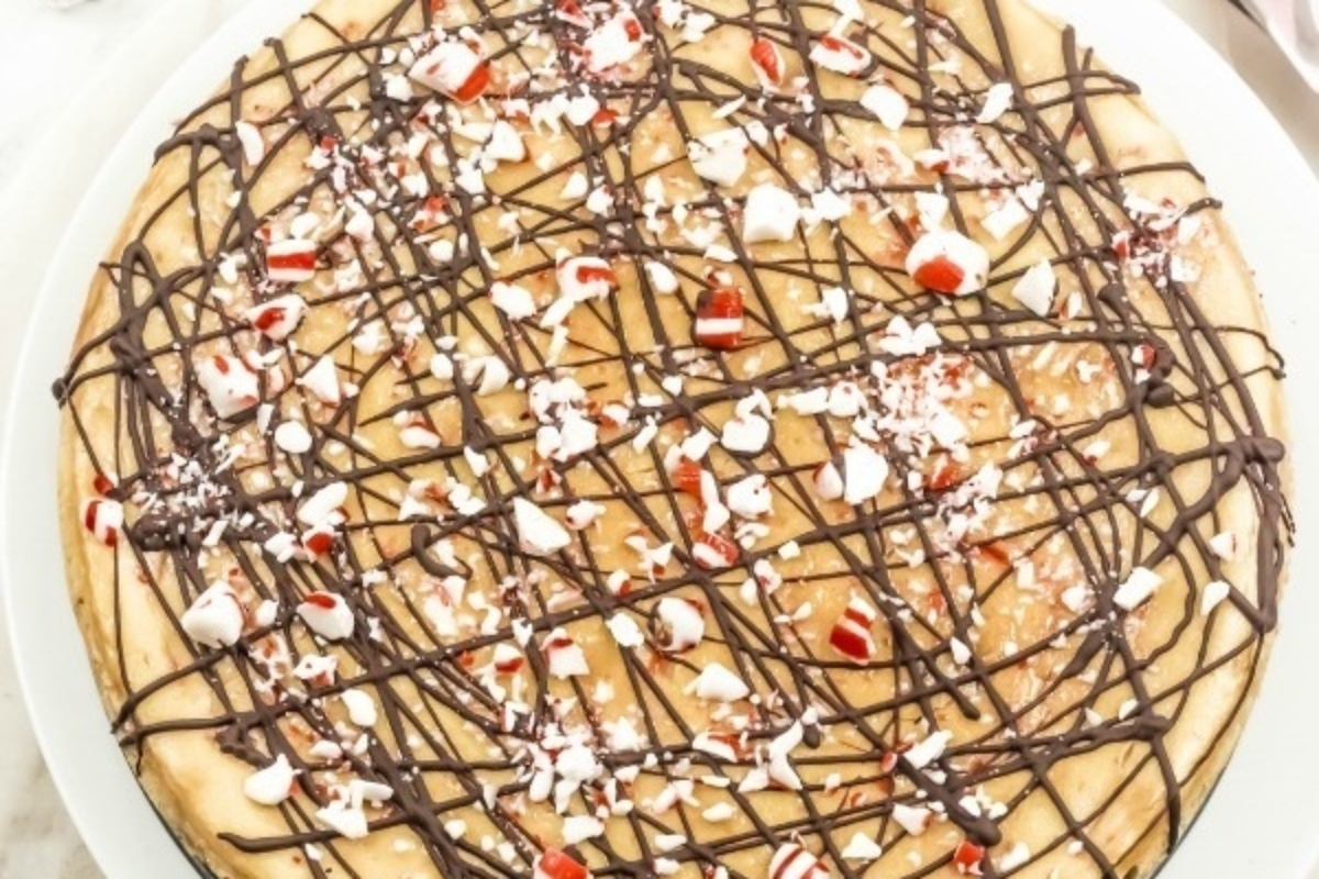 A Candy Cane peppermint cheesecake, topped with chocolate, on a white plate.