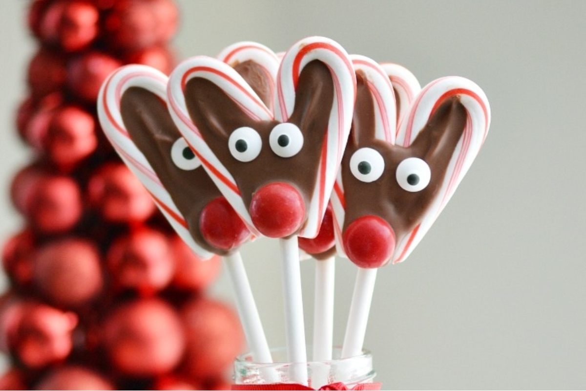 Reindeer lollipops in a candy cane vase with christmas decorations.