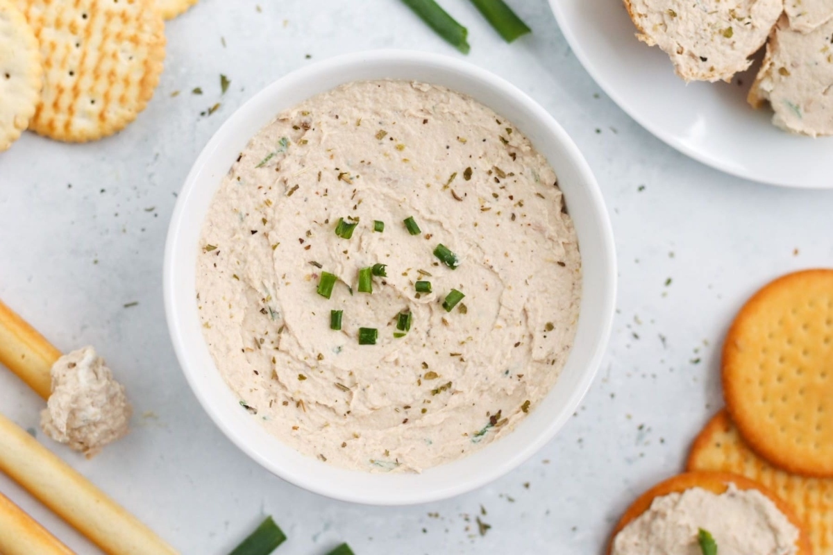 A bowl of dip with cream cheese and crackers.