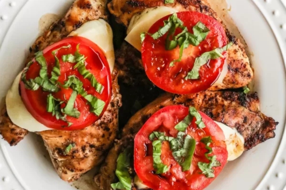 New Year's Eve Dinners: Grilled chicken breasts with tomatoes and basil on a white plate.