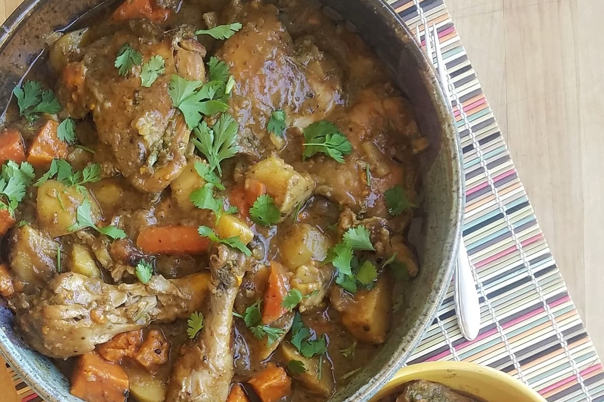         Description: A delicious pot of stew with cooked chicken and a variety of fresh vegetables sitting temptingly on a table.