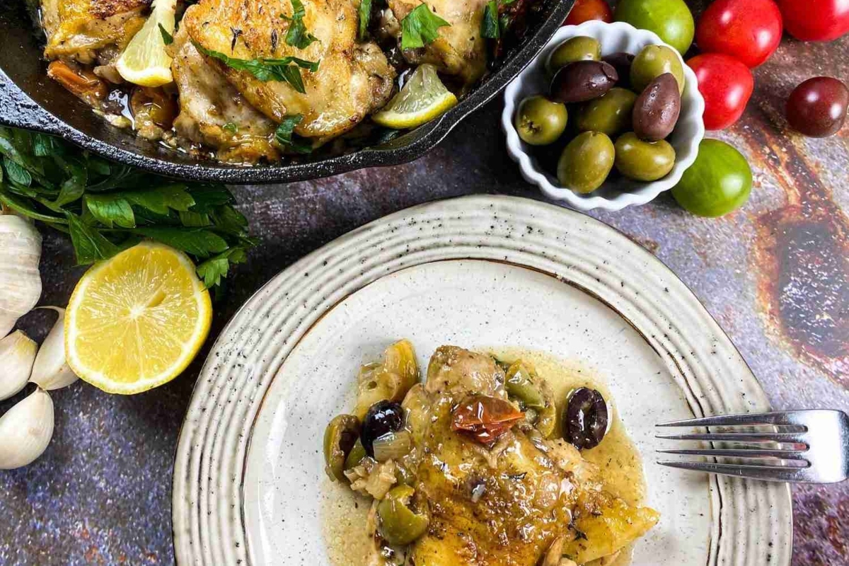 Tender chicken thighs with olives and lemon, prepared in a skillet.