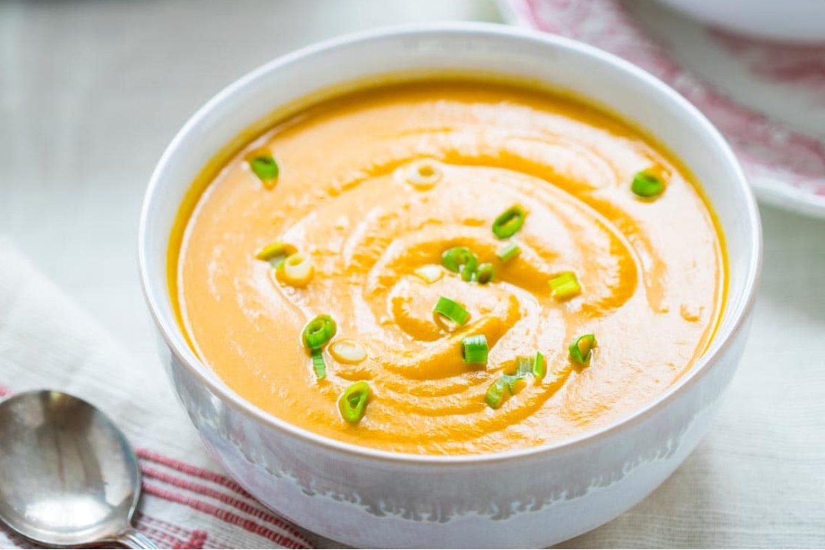 Potato soup in a white bowl with sprigs of chives.