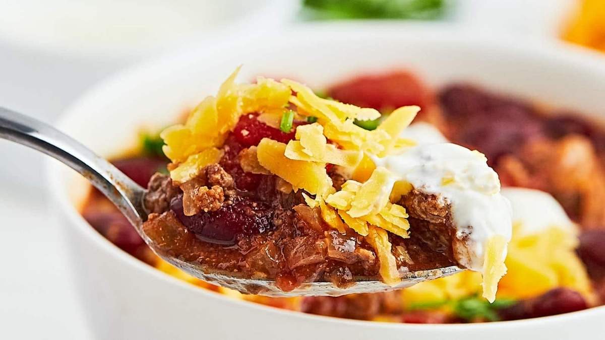 A shared round-up of comforting comfort food recipes, featuring a spoon full of chili with cheese and sour cream.