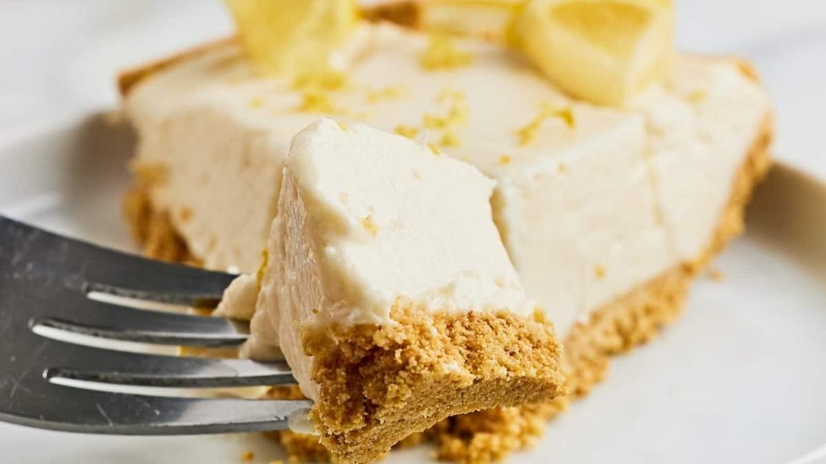 A shared slice of lemon pie on a plate with a fork.