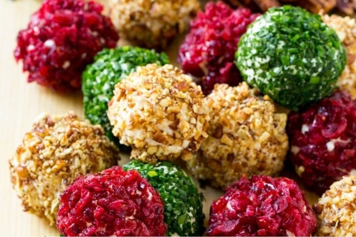 Festive cranberry nut balls arranged on a wooden cutting board.