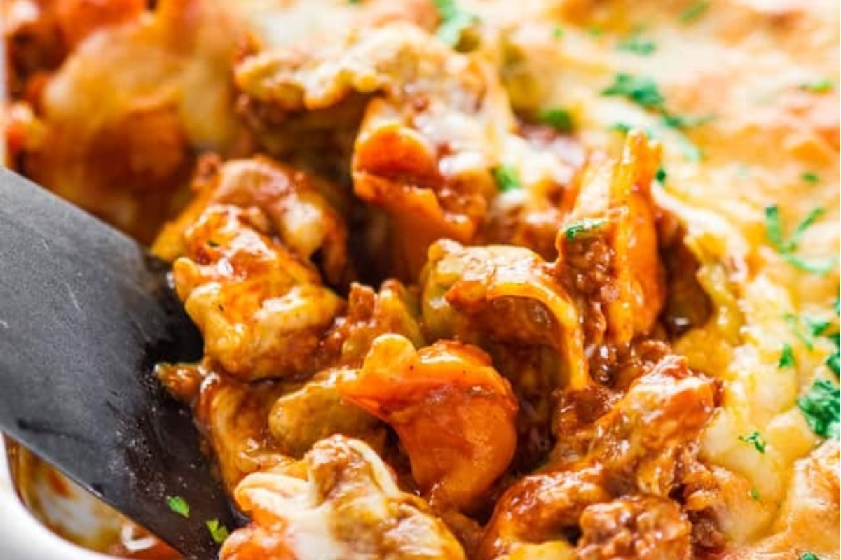 A tortellini fork is delicately taken out of a flavorful casserole dish, brimming with mouthwatering recipes.
