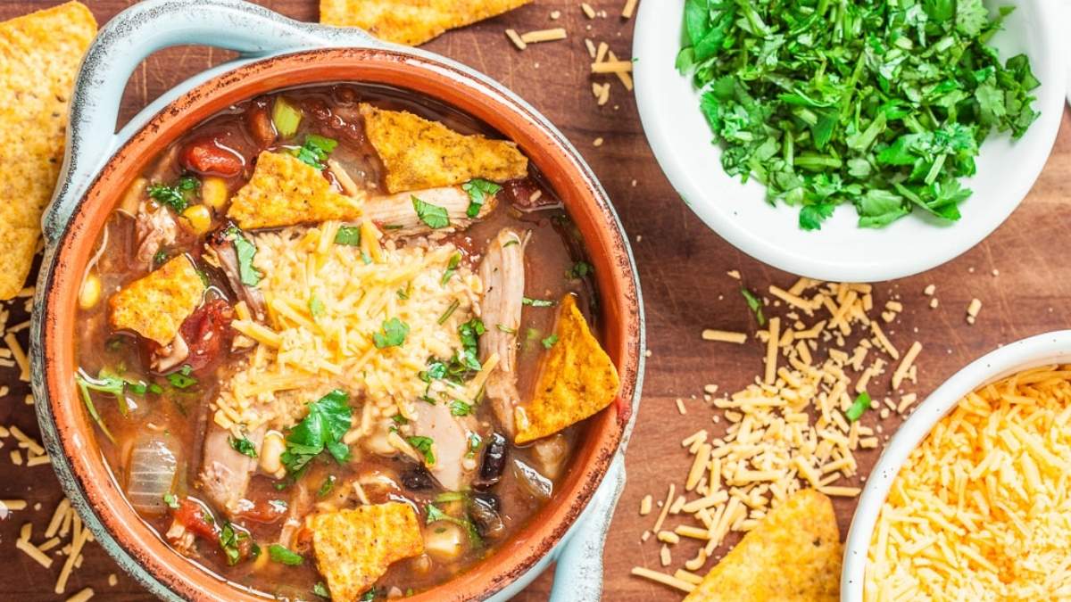 A bowl of mexican chicken soup with tortillas on a wooden table, perfect for soup lovers and those seeking flavorful recipes.